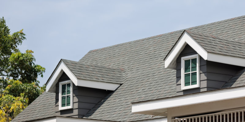 Roof shingles with garret house on top of the house. dark asphalt tiles on the roof background on afternoon time. dark asphalt tiles on the roof background